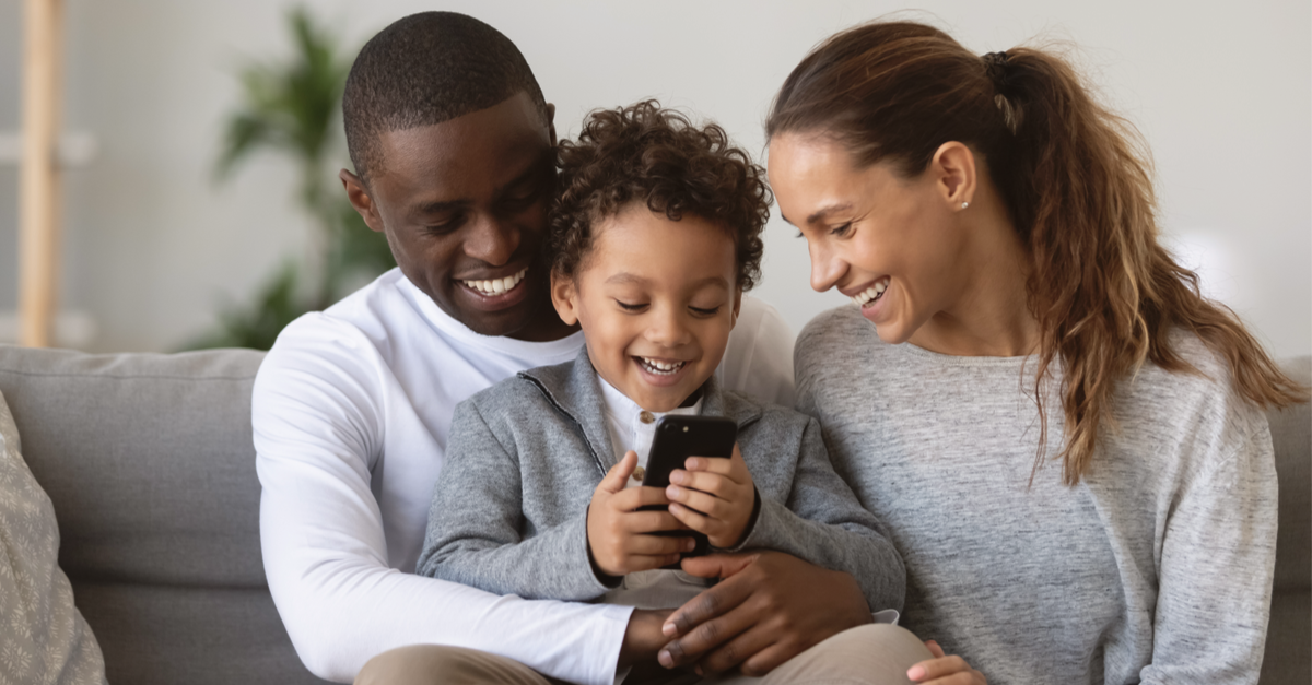 Parents and son smile while looking at cell phone