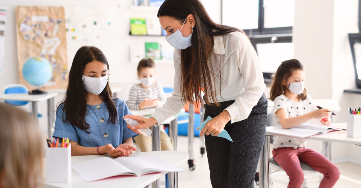 Teacher and students in the classroom with masks and sanitizer