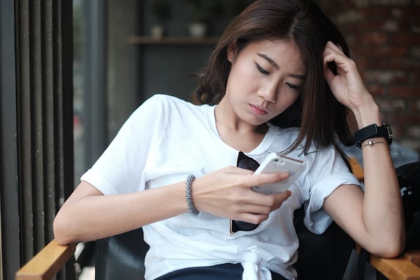Young Asian woman looking bored scrolling through phone